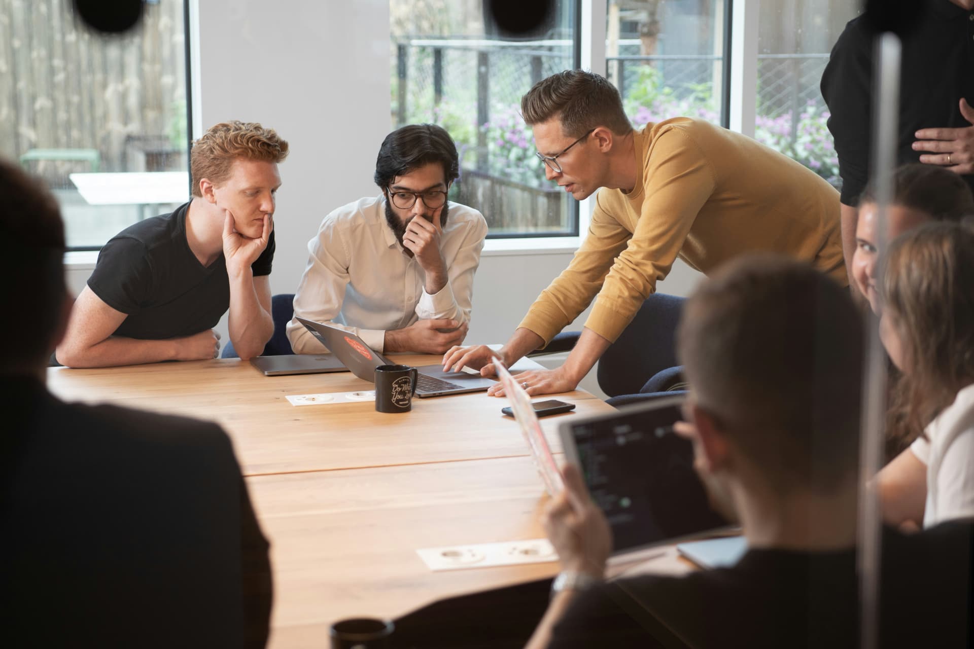 Equipo de marketing reunido alrededor de una laptop analizando una estrategia en una oficina luminosa